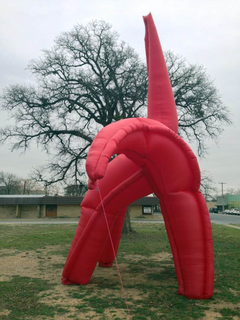 The Eagle has Landed, HOMECOMING! Committee, 2014: close-up of the red inflatable eagle beside a bare winter tree on an overcast day